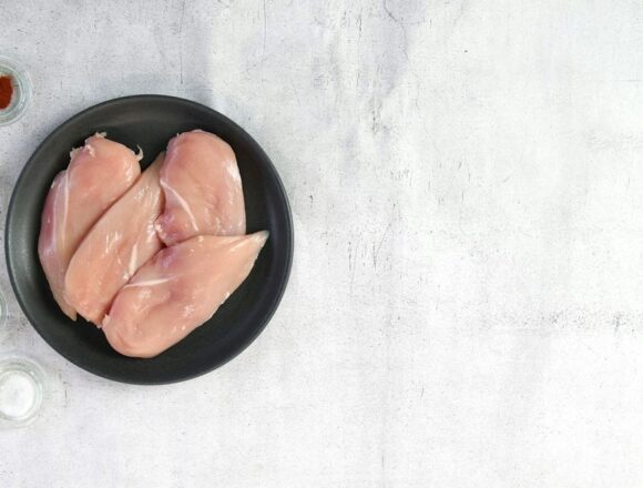carne-pui-china-ue Piept de pui crud într-un bol negru, lângă condimente