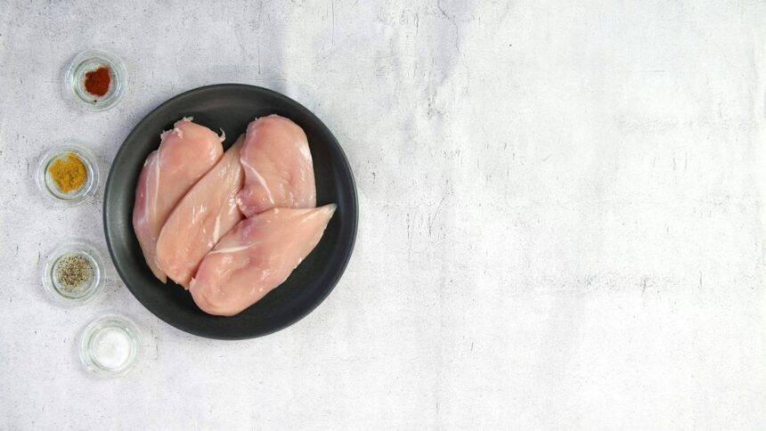 carne-pui-china-ue Piept de pui crud într-un bol negru, lângă condimente