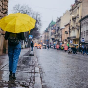 Persoană cu umbrelă pe o stradă udă, în timpul ploilor aduse de codul galben din octombrie 2026