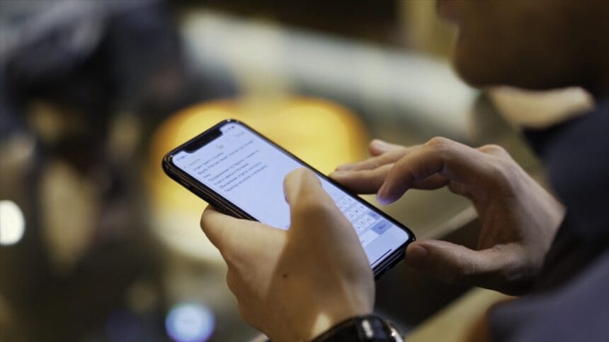 Persoană care citește un mesaj pe telefon, ilustrând documentul fals despre încorporarea tinerilor Persoană care citește un mesaj pe telefon, ilustrând documentul fals despre încorporarea tinerilor