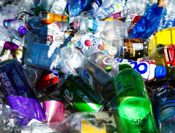 returnare-ambalaje-sgr Grămadă de sticle PET și doze de băuturi pregătite pentru returnare și reciclare