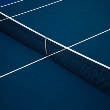 Teren de tenis cu suprafață hard albastră și fileul văzut de sus