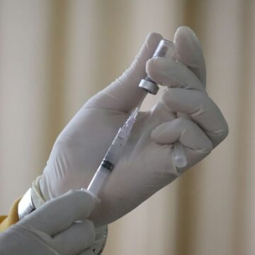 vaccin-antigripal-2026-2027 Cadru medical cu mănuși pregătind o seringă cu vaccin antigripal