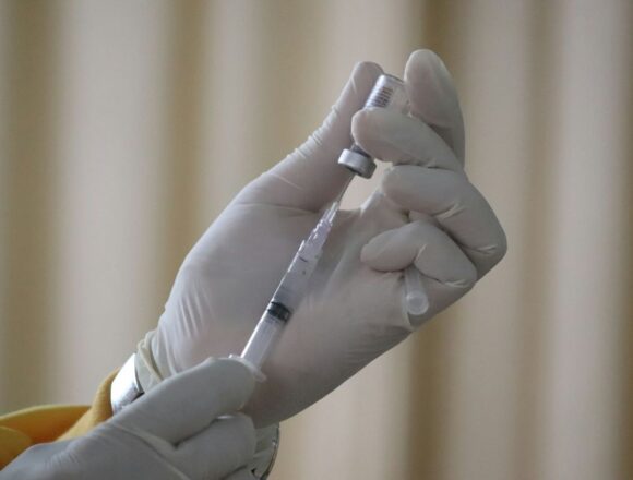 vaccin-antigripal-2026-2027 Cadru medical cu mănuși pregătind o seringă cu vaccin antigripal