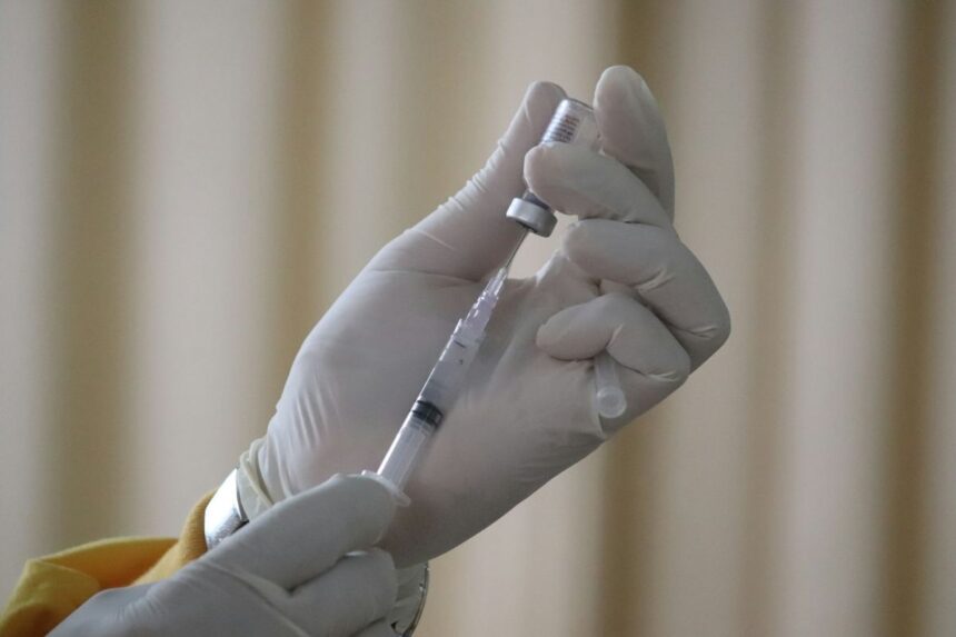 vaccin-antigripal-2026-2027 Cadru medical cu mănuși pregătind o seringă cu vaccin antigripal